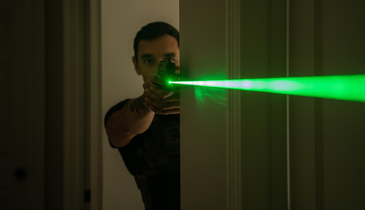 Shooter with green laser sighted pistol